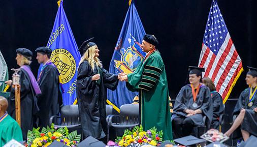 Graduate crossing the stage shaking 总统Ramsammy's hand